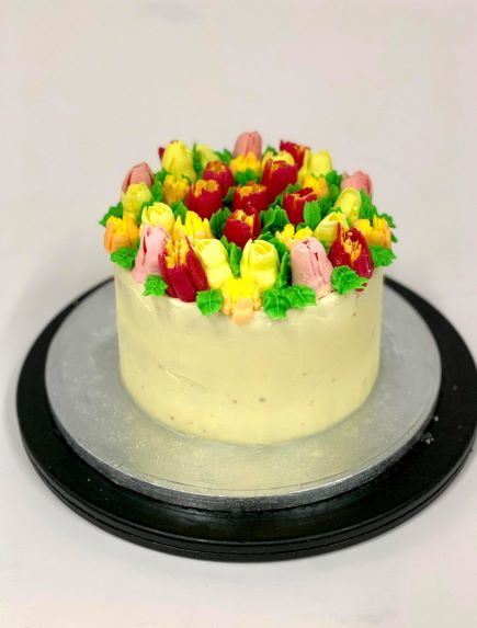 The London Cake Academy shows bright coloured flowers piped on a cake