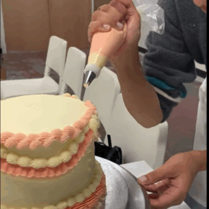 Student decorating her cake with a piping bag at the london cake academy