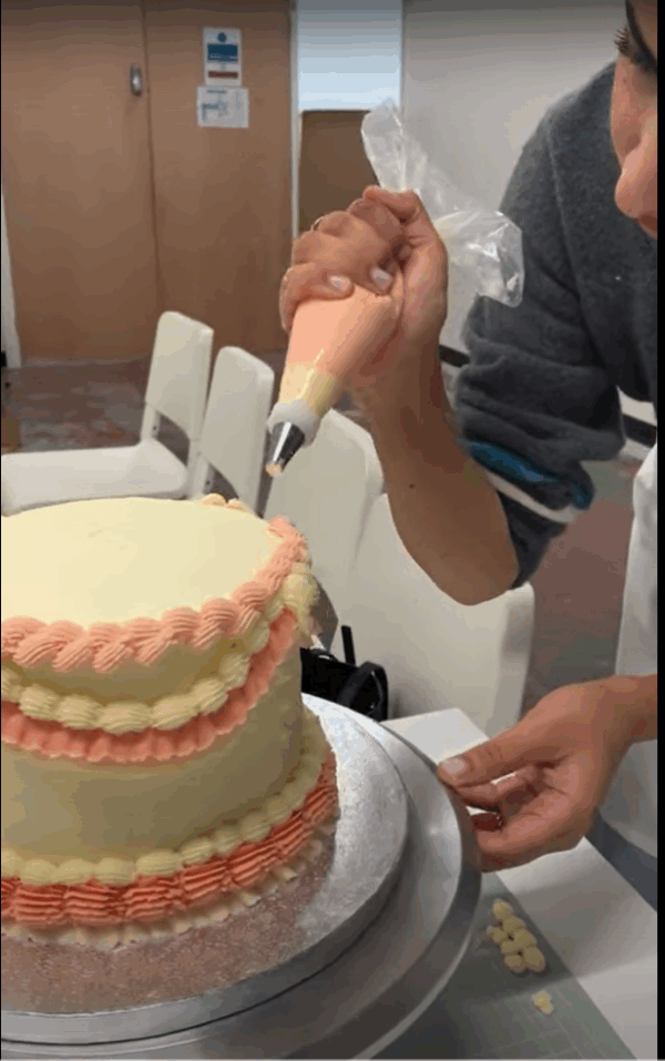 Student decorating her cake with a piping bag at the london cake academy